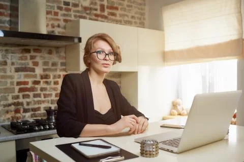 A girl in glasses gesturing while talking to her colleagues in a video call. Stock Photos