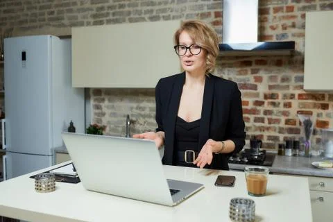 A girl in glasses gesturing while talking to her colleagues in a video call. Stock Photos