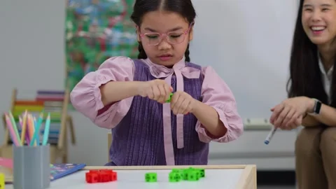 Girl with Glasses Learning Math Using Colorful Counting Blocks in Classroom Stock Footage 329216075