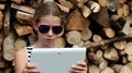 Girl in glasses near stack of firewood with tablet computer HD Footage