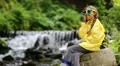 Girl in glasses in the shape of hearts sits near river and talks on cell phone HD Footage