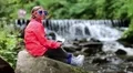 Girl in glasses in the shape of hearts sits near river and talks via tablet pc HD Footage
