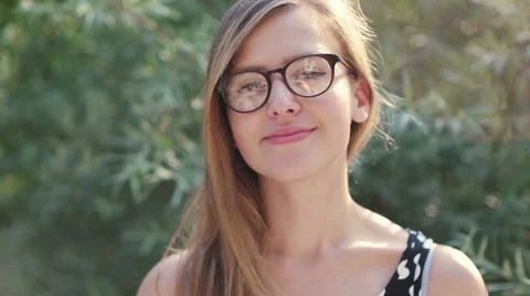 Girl with glasses smiling to the camera, nerd girl enjoying the sun Stock Footage 53693448