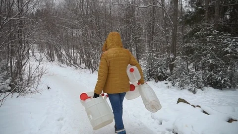 The girl goes for water to the artesian source. She collected a lot of water can Stock Footage 99632402