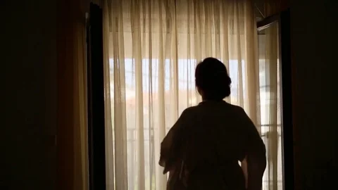 The girl goes to the window and opens the curtains. Silhouette o Stock Footage 75259846