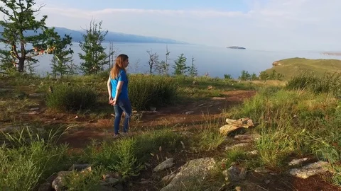 The girl going down the path to the water. Green hills of Ogoi Island, Lake Vídeos de archivo 128410104