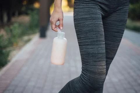 Girl in gray leggings holds a pink water bottle close-up Stock Photos