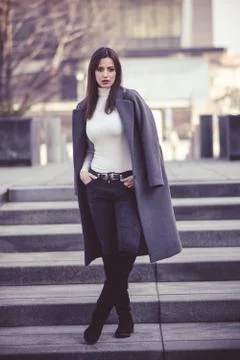 Girl in grey coat standing onthe stairs Stock Photos