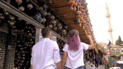 Girl with a guy walking through the bazaar and touching toys Stock Footage 90374247
