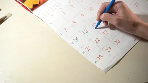 Girl hand Write down the all day on the paper calendar using a red pen. Very Stock Footage 240580342