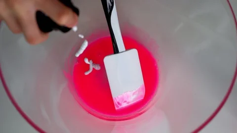 The girl hands make a large pink slime in a bowl on a white table Stock Footage 127596476