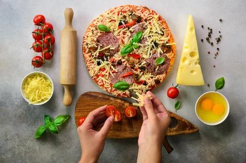Girl hands making, decopating, preparing pizza with basil leaves on light g.. Stock Photos