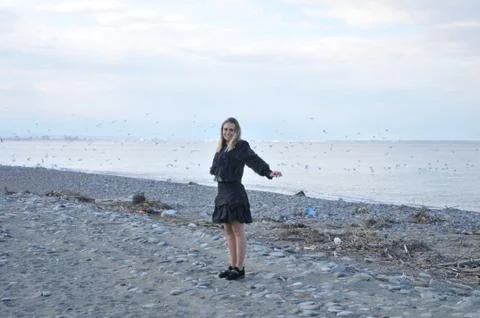 A girl is happy on the beach. She is free and behind her is full of birds that s Stock Photos