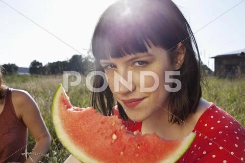Girl has slice of melon in her hand with bike marks on it Stock-Fotos