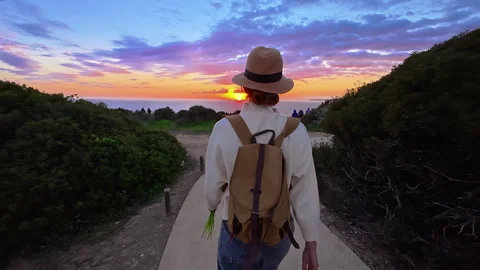 A girl in a hat and with a backpack goes to the edge of a cliff on Ponta de Stock Footage 311031710