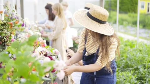 Girl in hat chooses flowers from vases at masterclass Stock Footage 136653553