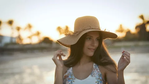 Girl with a hat posing in front of the camera at sunset 動画素材 129025876
