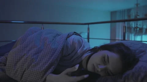 Girl have difficulty falling asleep A Young Woman Lies in Bed at Night and Stock Footage 164453541