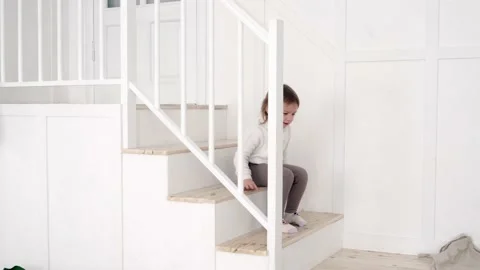 Girl having fun sliding down the stairs at home Video stock 239454524