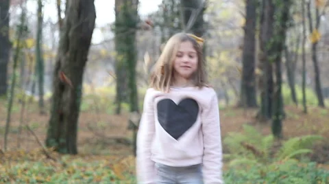 Girl having fun throwing leaves and jumping in the park Stock Footage 59553827