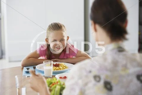 Girl Having Meal With Mother Stock Photos
