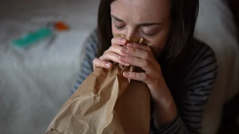 Girl having panic attack, fear and lack of air, deep breathing into paper bag Stock Footage 126997707