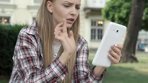 Girl having problem with tablet in the park and looks irritated, steadycam shot Stock-Footage 79290256