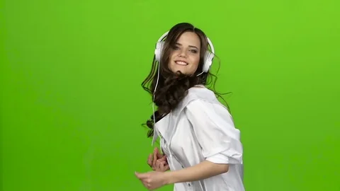 Girl with headphones in her ears whirls in dance she loves music. Green screen Stock Footage