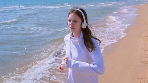 Girl in headphones music jogging at sea sand beach sport run outdoor training. Stock Footage