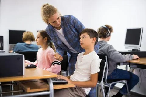Girl helping boy with computer problem Stock Photos