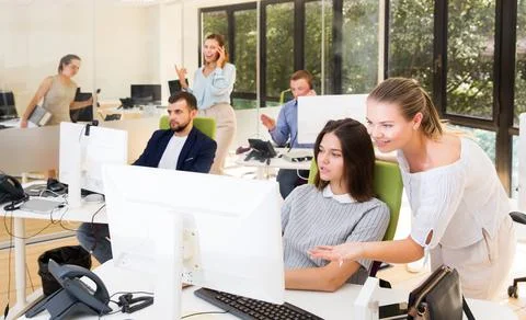 Girl helping female colleague in work with computer Stock Photos