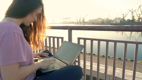 Girl with her laptop near coastline of the port in the morning Stock Footage