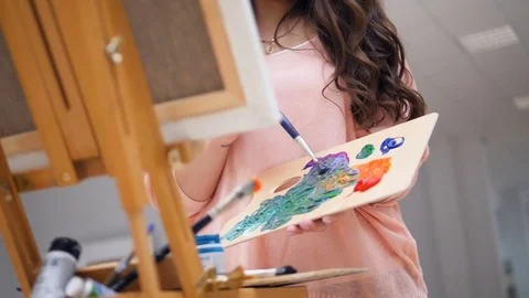 Girl holding a brush, mixing colors for her picture. Stock Footage