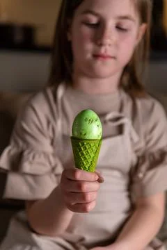 Girl holding an Easter egg in a colored ice cream cone Stock Photos
