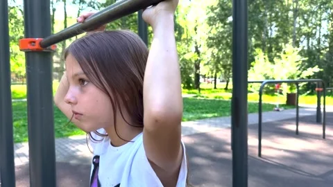 Girl holding hands on pull-up bar at outdoor playground Stock-Footage 317288532