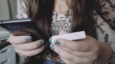 Girl Holding a Pregnancy Test and Texting on Her Smartphone The Results Stock Footage