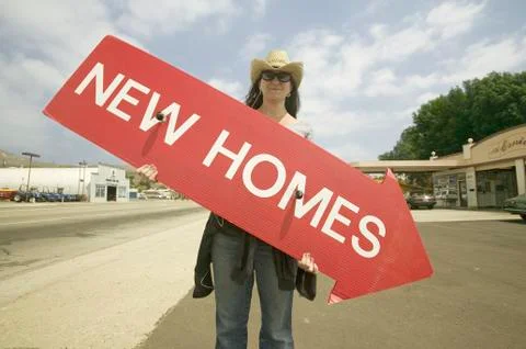 Girl holding red sign with arrow pointing down, that reads New Homes For Sale in Stock Photos