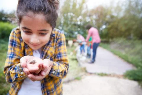 Girl Holding Small Frog As Group Of Children On Outdoor Activity Camp Catch And Stock Photos