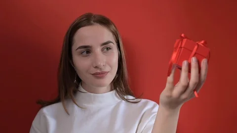 The girl holds a gift in her hands and smiles. Young beautiful smiling woman Stock Footage 127458564