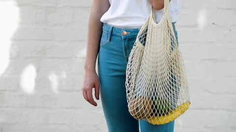 Girl holds reusable mesh string knitted shopping bag with fruits and vegetables Stock Footage 112049998