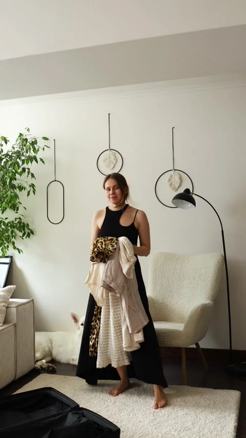 A girl holds a stack of clothes and shows it to the camera at home Stock Footage 280559100