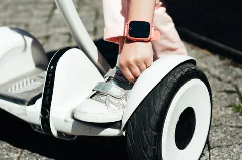 Girl on hoverboard using smart watch pink color Stock Photos