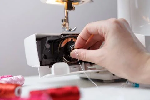 Girl inserts bobbin in sewing-machine Girl inserts bobbin in sewing machin... 写真素材