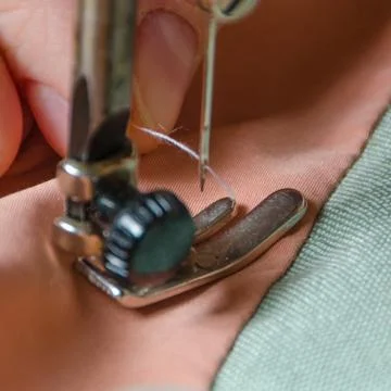 The girl inserts the thread into the needle of the sewing machine Fotos de archivo
