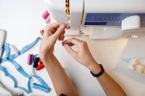 Girl inserts thread in sewing-machine Girl inserts thread in sewing machin... Foto stock