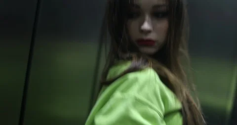Girl inside elevator looking at mirror adjusting hair and clothing making her Stock Footage 120745753