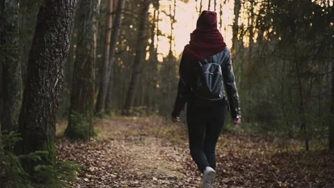 Girl in a jacket and with a backpack walks along a forest path at sunset. Stock Footage 142126431