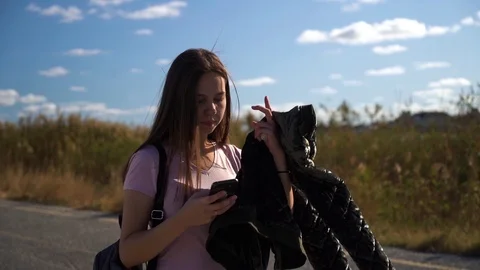 Girl with jacket in hand using mobile phone walking Stock Footage 116792294