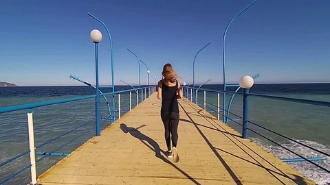 Girl jogging on pier at sunset, slow motion hd video Stock Footage 75154341