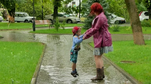 A girl is jumping with a boy in a puddle. Video stock 86150656